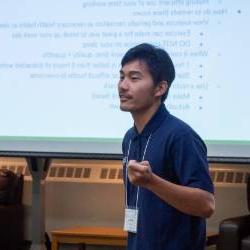 Presenter wearing a lanyard speaks at a past Colloquium